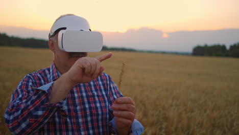 Senior-adult-farmer-uses-virtual-reality-for-farming-by-holding-a-spikelet-in-his-hands-and-pressing-his-finger-on-the-grain-using-modern-technology-and-graphics.